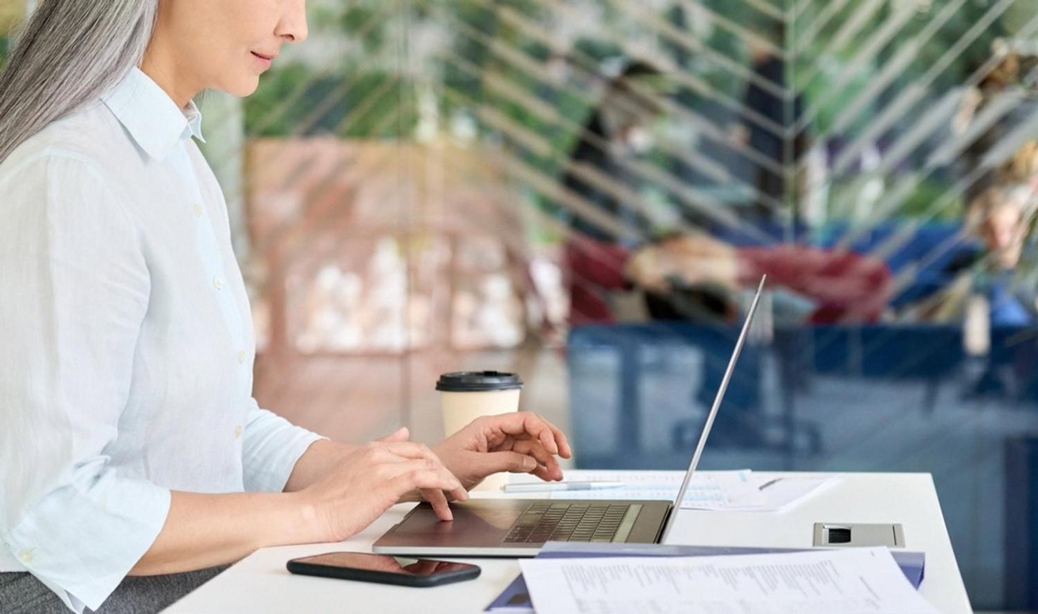 Woman researching a UAE company's online reviews on a laptop in a cafe