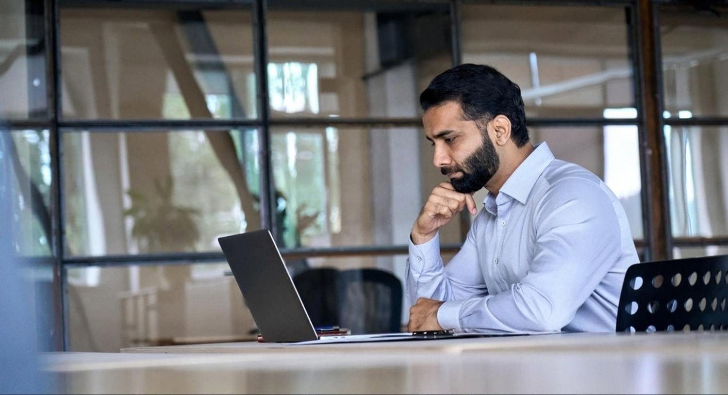 Businessman in a Dubai office reading company mentions on his laptop